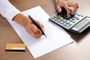 Closeup of woman calculating on calculator with credit card